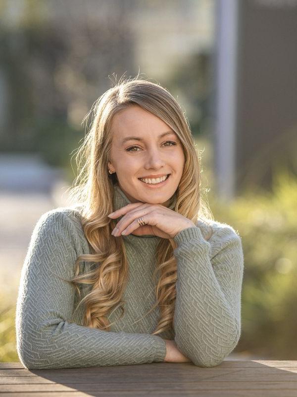 Photos shows the smiling face of Shelby Yaceczko. She is wearing a sage green cable-knit turtleneck sweater.